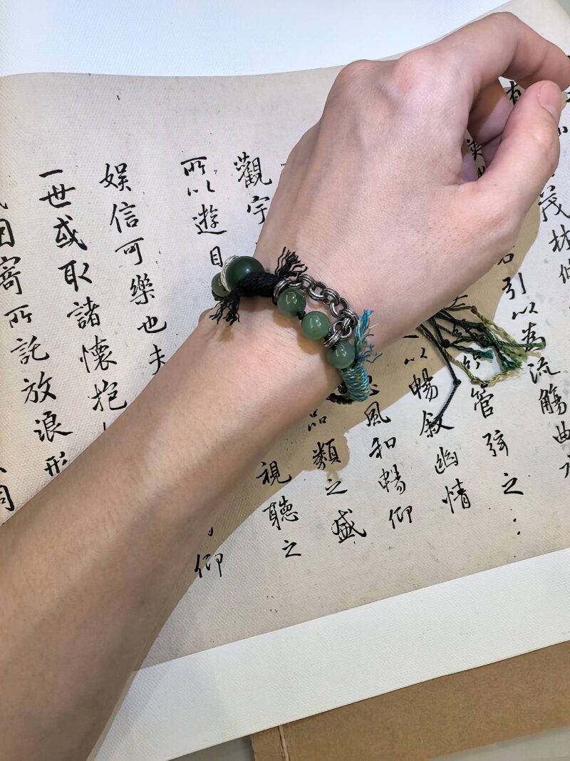 Greeting bracelet from EBIG Jewel on wrist held against writing.