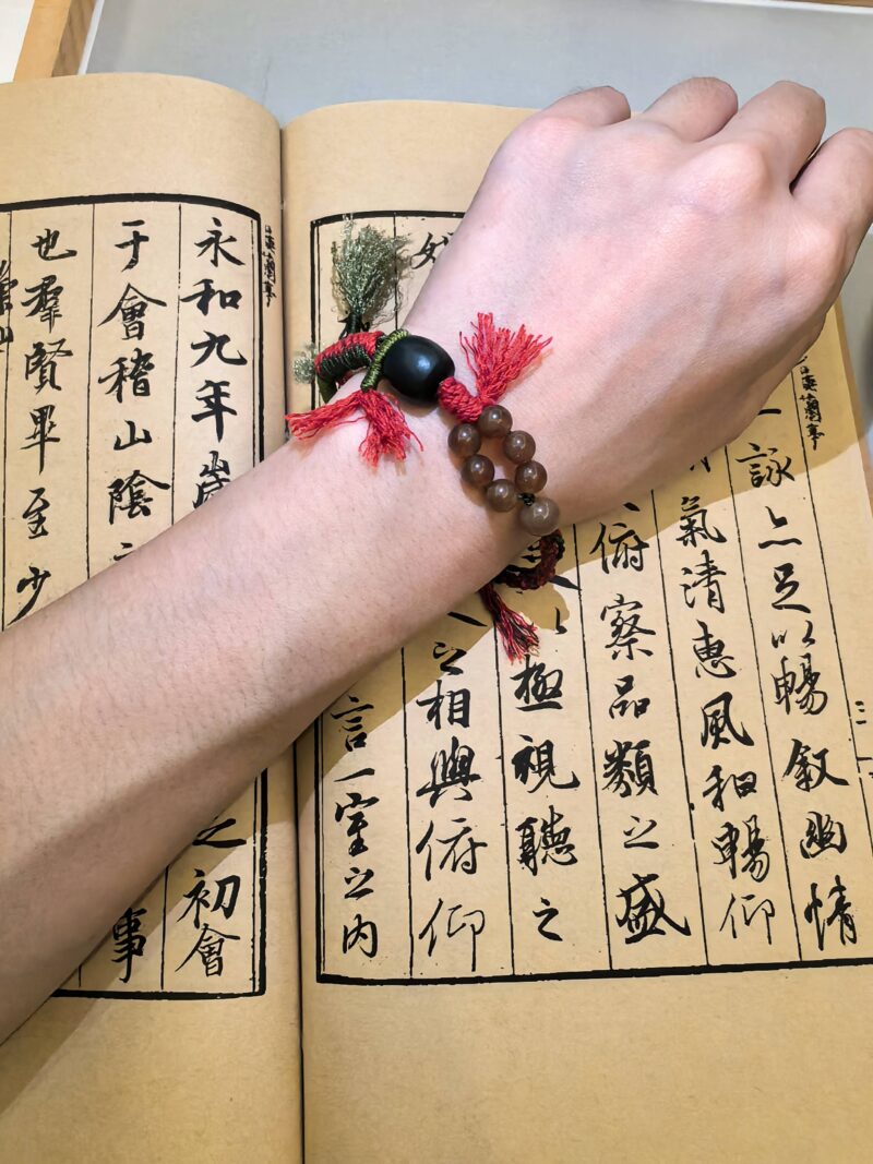 Blessing bead bracelet from EBIG Jewel being worn on wrist and held against book.