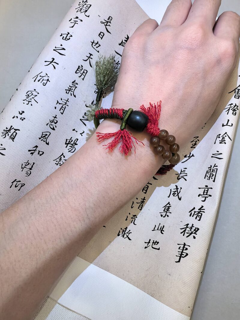 Blessing bead bracelet from EBIG jewel being worn and held against writing.